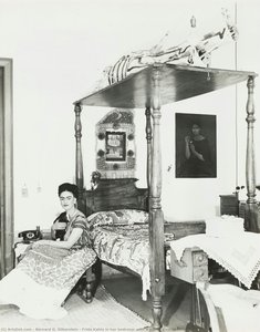 Frida Kahlo in her bedroom with a young goat in her arm