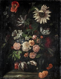 Roses, tulips, poppies, a sunflower and other flowers in a glass vase on a stone ledge