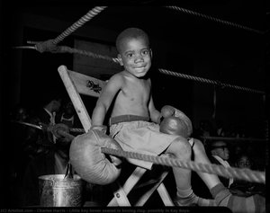 Little boy boxer seated in boxing ring, possibly in Kay Boys