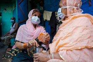 A woman provides ORS (Oral Rehydration Salts) for her mother in a Delhi slum