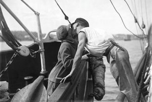 Man and woman kissing across two vessels
